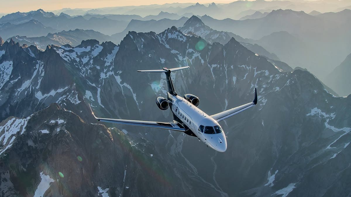 Business jet flying over snowy mountains